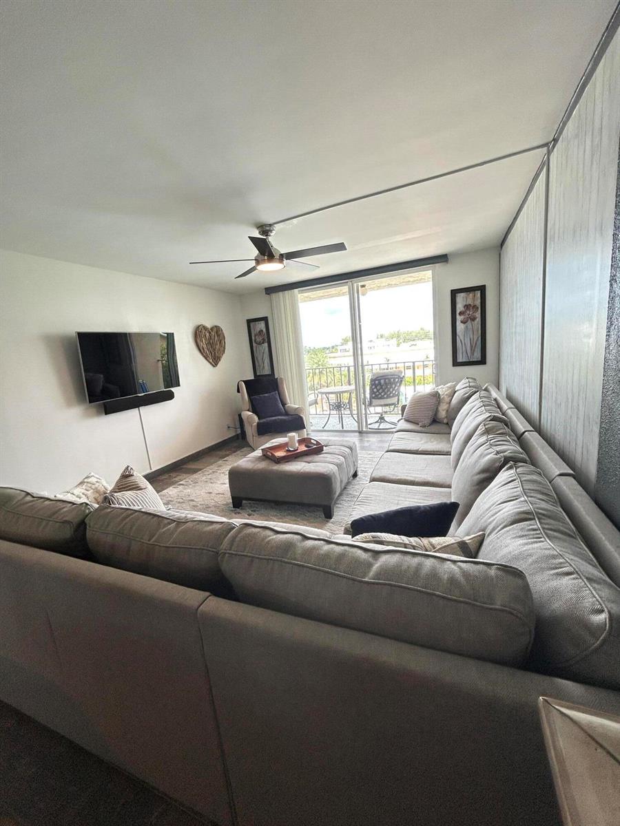 A living room features a large sectional sofa, a central ottoman, and a sliding glass door — 1009 N Ocean Boulevard N # 401, Pompano Beach FL 33062, POMPANO BEACH, FL