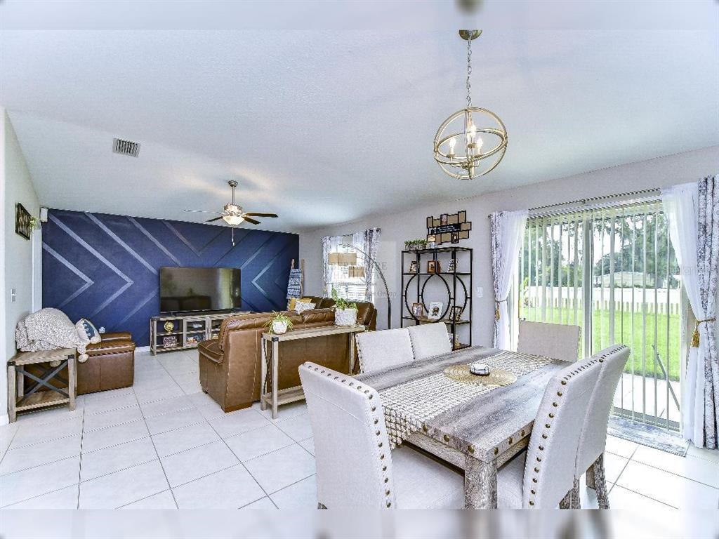 An open-concept living and dining room features a blue accent wall and tile flooring — 1412 TAHITIAN SUNRISE DRIVE, PLANT CITY, FL