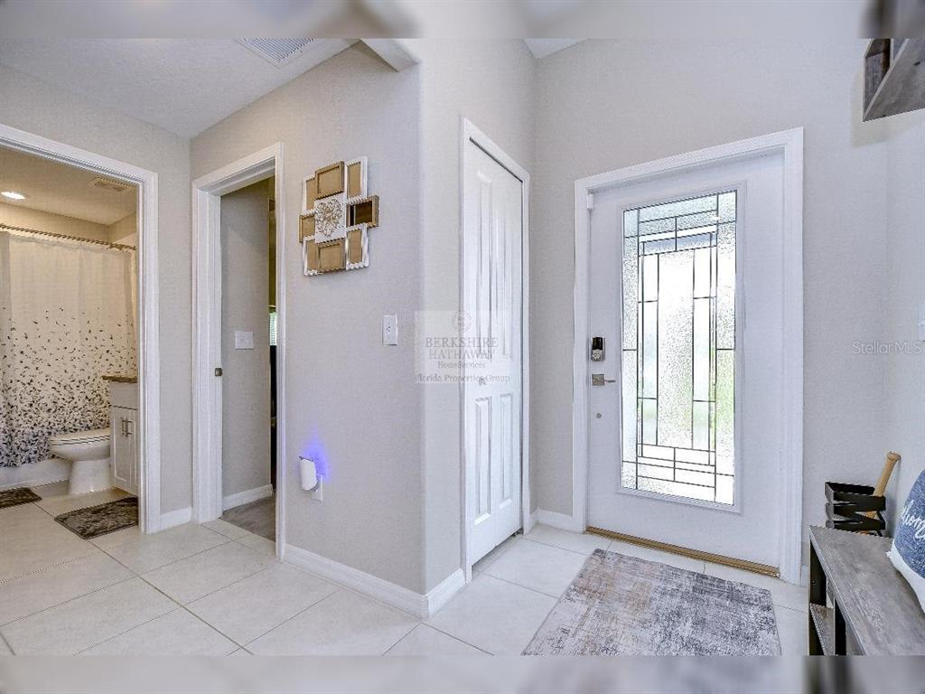 An entryway features a white front door with glass panels, tiled floors, and a nearby bathroom — 1412 TAHITIAN SUNRISE DRIVE, PLANT CITY, FL