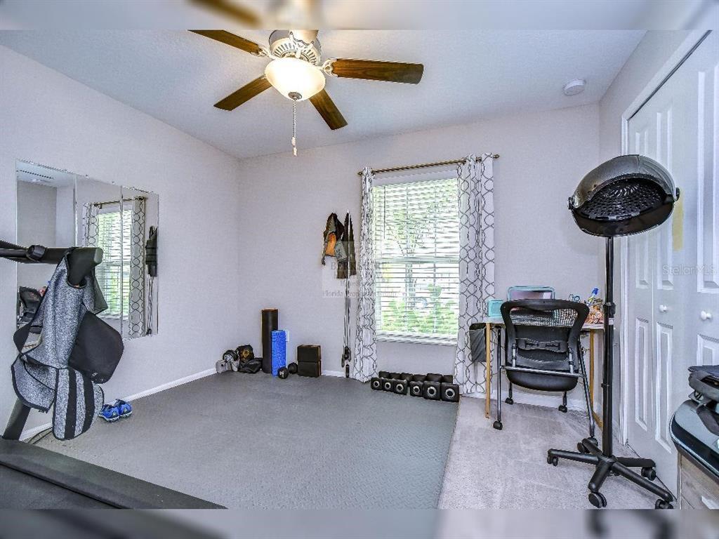 A carpeted room features a ceiling fan, a treadmill, a desk, and a salon hair dryer — 1412 TAHITIAN SUNRISE DRIVE, PLANT CITY, FL