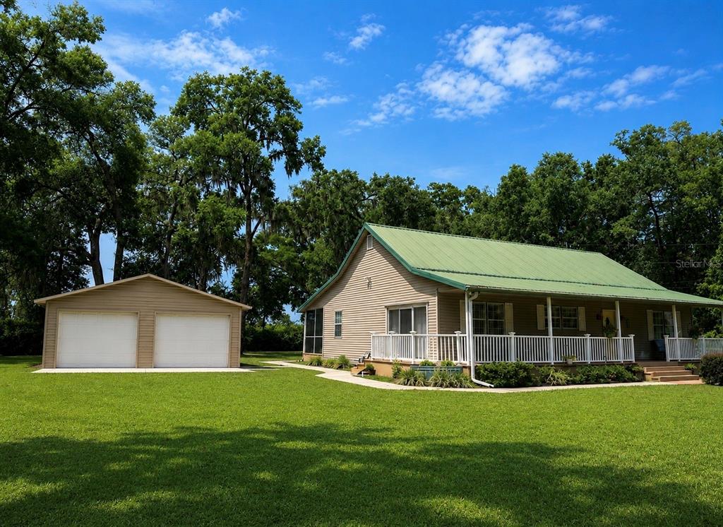 A tan house with a green metal roof and a detached two-car garage — 18848 SW 60TH STREET, DUNNELLON, FL