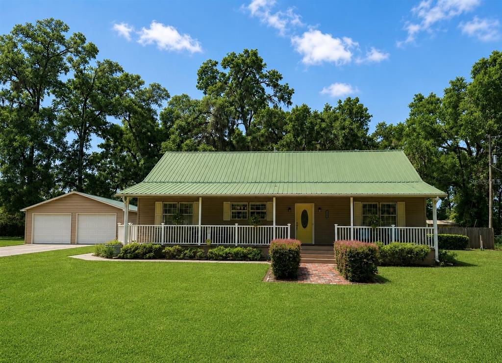 A one-story house with a green metal roof, front porch, and detached two-car garage — 18848 SW 60TH STREET, DUNNELLON, FL
