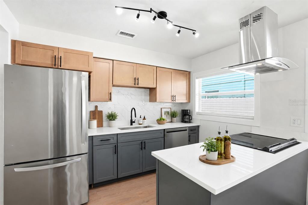 A kitchen features two-toned cabinets, stainless steel appliances, a white island, and a track light — 695 41ST STREET N, ST PETERSBURG, FL