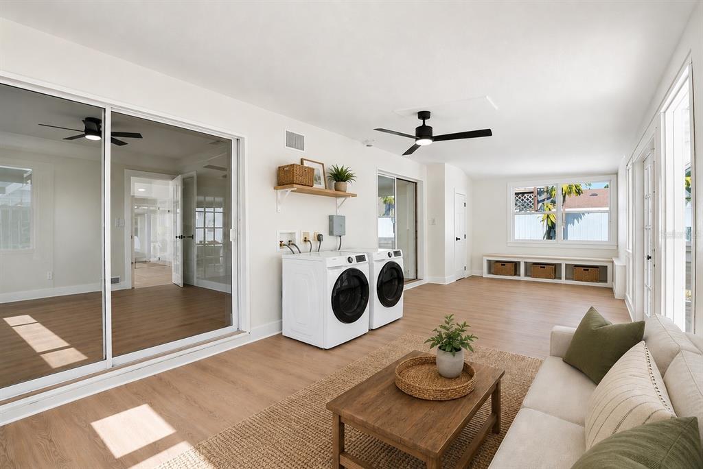 A sunroom features a laundry area with white appliances, wood-look flooring, and a sofa — 695 41ST STREET N, ST PETERSBURG, FL