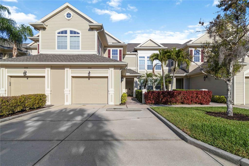 A two-story tan townhouse with a two-car garage and a paved driveway — 7954 TYBEE COURT UNIT 7954, UNIVERSITY PARK, FL