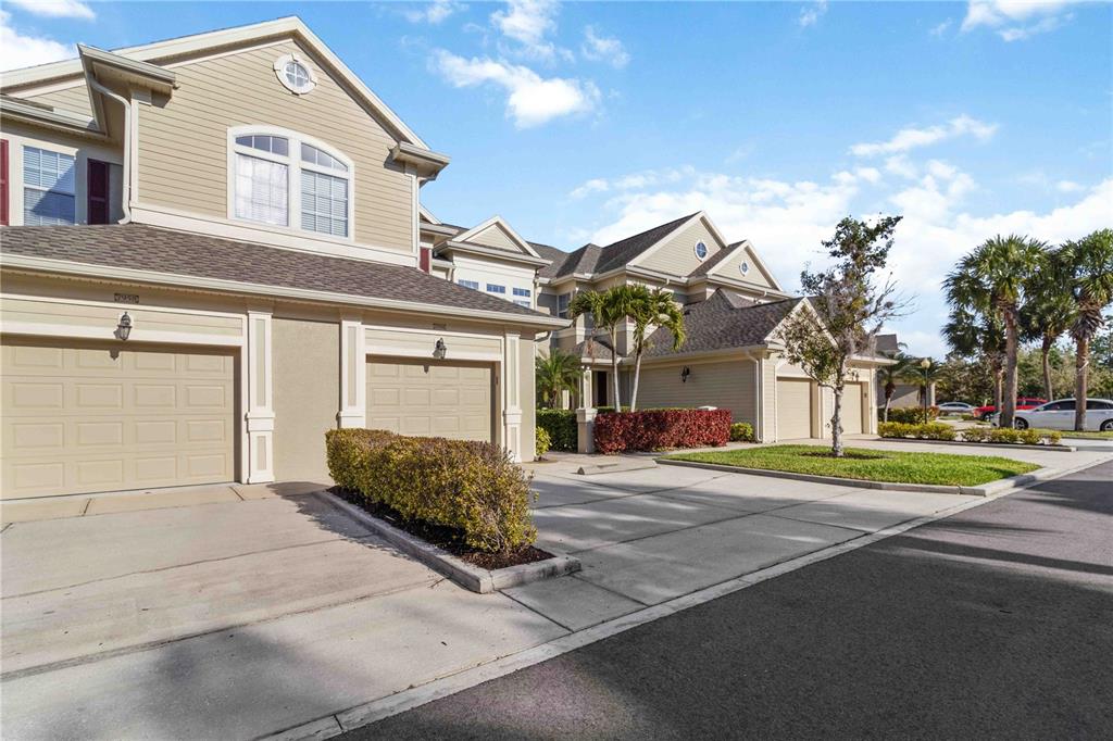 A multi-unit residential building with beige siding, attached garages, and a concrete driveway — 7954 TYBEE COURT UNIT 7954, UNIVERSITY PARK, FL