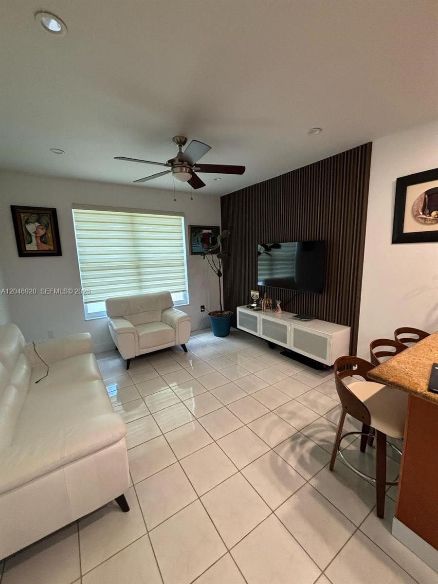 A living room features a white sofa, a matching armchair, and a wood-slatted accent wall — 15986 SW 71st Ter, Miami FL 33193, MIAMI, FL