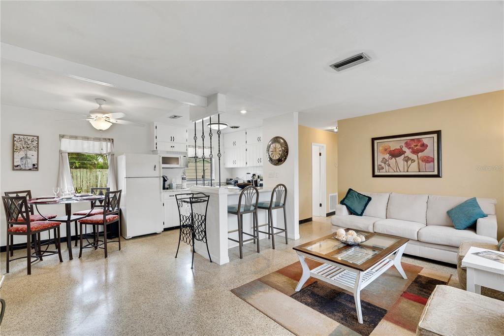 An open-concept living and dining area features white cabinetry, a breakfast bar, and terrazzo flooring — 2830 SIESTA DRIVE, VENICE, FL