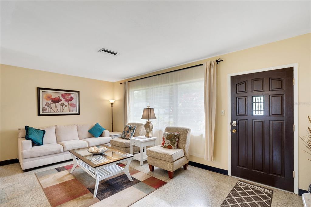 A living room features a beige sofa, two patterned armchairs, and a dark wood door — 2830 SIESTA DRIVE, VENICE, FL
