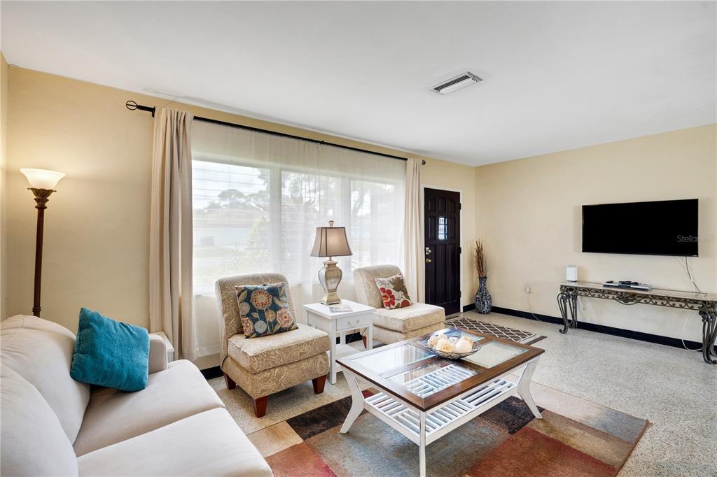 A living room features a sofa, two armchairs, a coffee table, and a wall-mounted television — 2830 SIESTA DRIVE, VENICE, FL