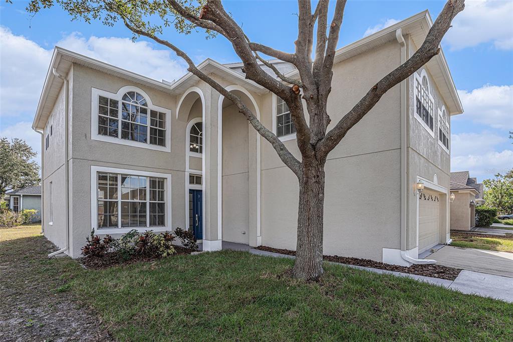 A two-story beige stucco house with a blue front door and an attached garage — 8602 SANDY PLAINS DRIVE, RIVERVIEW, FL