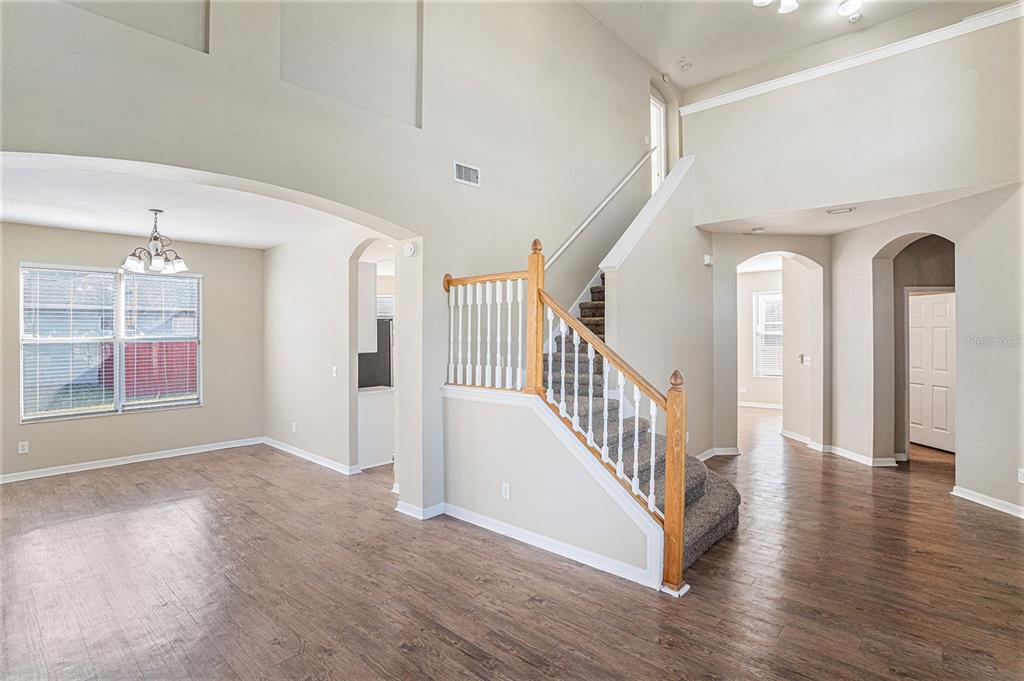 An interior view shows a living area with wood-look flooring, a staircase, and arched doorways — 8602 SANDY PLAINS DRIVE, RIVERVIEW, FL