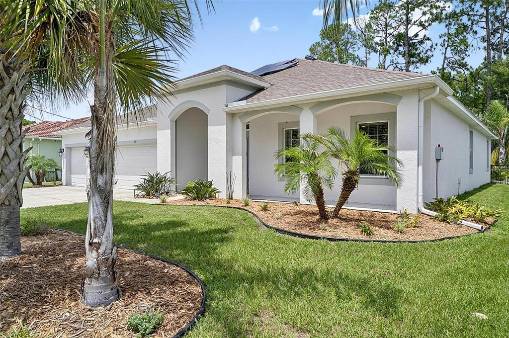 A single-story house with a white stucco exterior, a two-car garage, and palm trees — 34 BUNKER HILL DRIVE, PALM COAST, FL