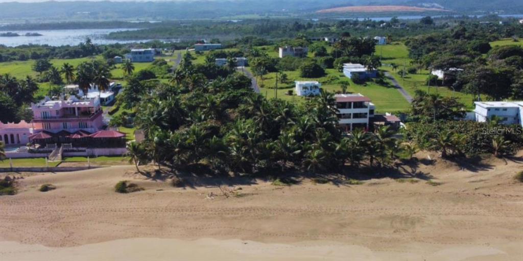 An aerial view shows beachfront houses surrounded by palm trees near a sandy coastline — Carr. 681 KM 11.7 BO. ISLOTE SEC. MELILLA, ARECIBO, PR
