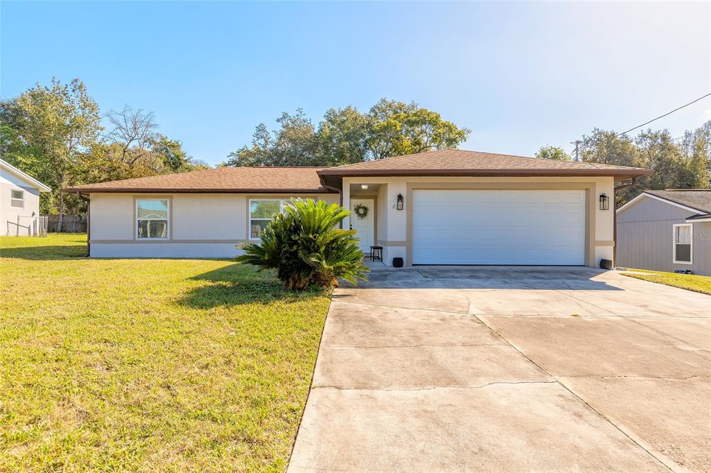 A single-story house with a beige exterior, a two-car garage, and a concrete driveway — 235 LANCASTER AVENUE, ORANGE CITY, FL