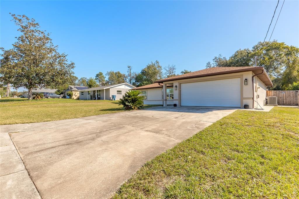 A single-story house with a white garage door, concrete driveway, and a large front lawn — 235 LANCASTER AVENUE, ORANGE CITY, FL