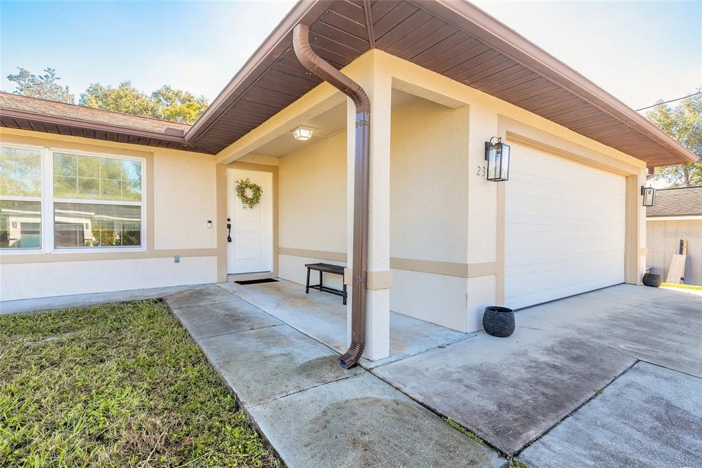 The exterior of a single-story home features a white front door, garage, and concrete walkway — 235 LANCASTER AVENUE, ORANGE CITY, FL