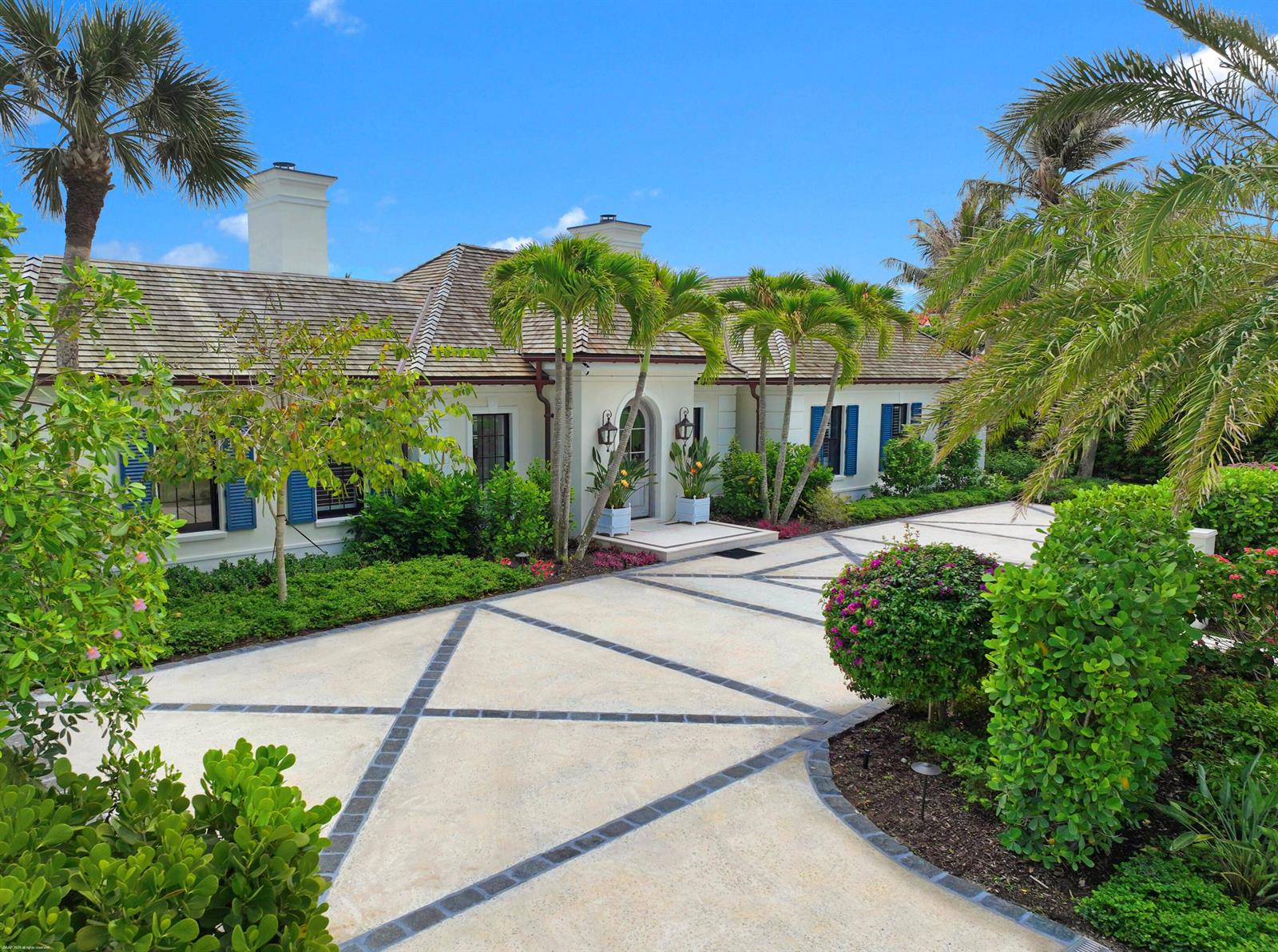 A single-story house with a patterned concrete driveway, blue shutters, and surrounding palm trees — 55 Links Road, Jupiter Island FL 33455, JUPITER ISLAND, FL