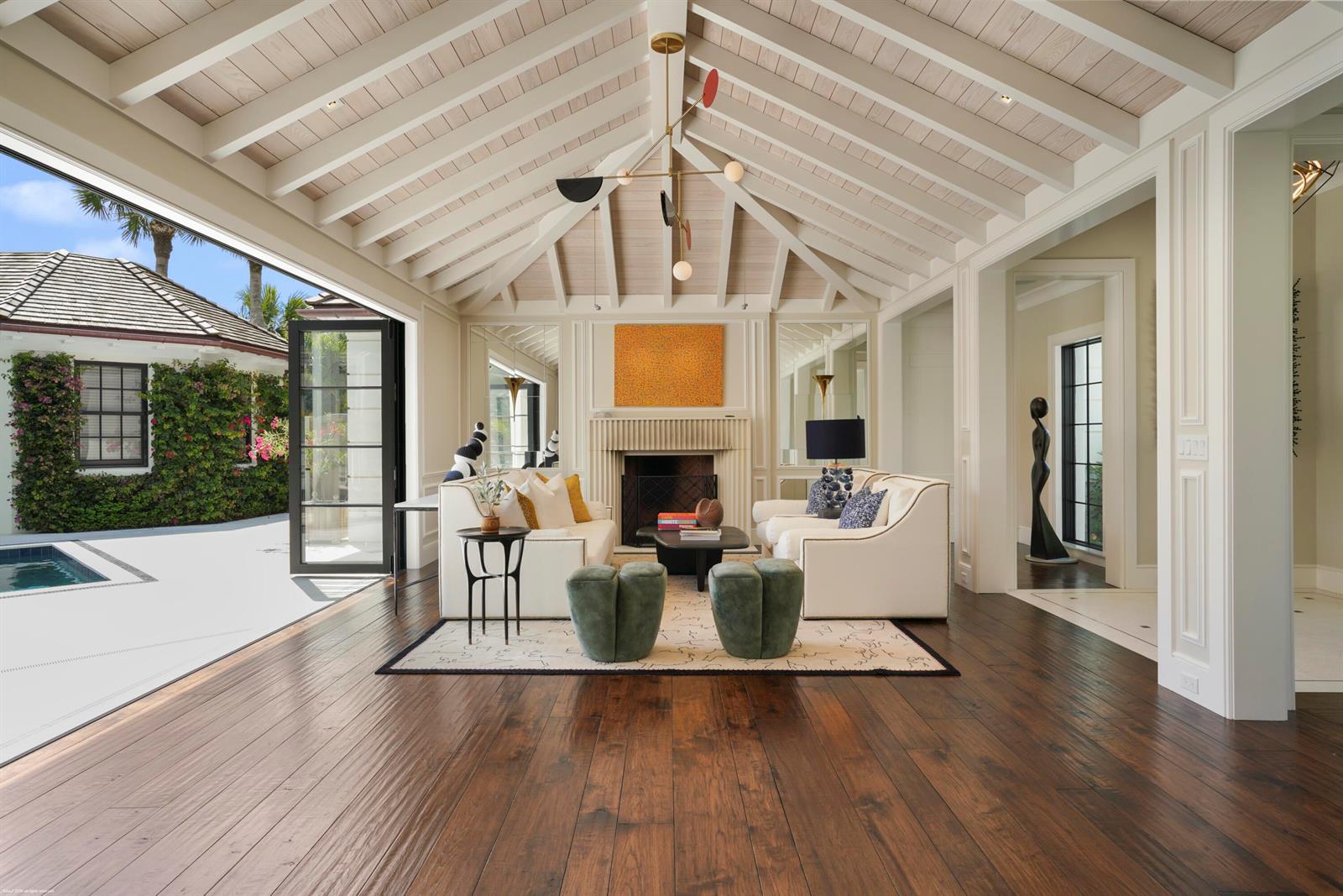 A living room with a vaulted ceiling, fireplace, and large glass doors opening to a pool — 55 Links Road, Jupiter Island FL 33455, JUPITER ISLAND, FL