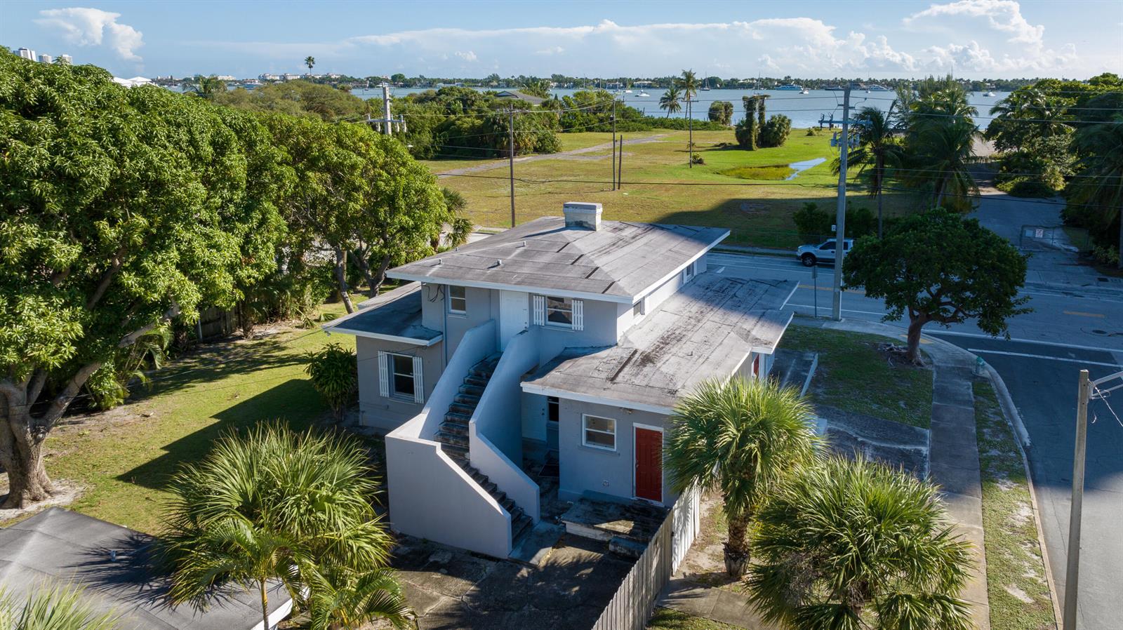 An aerial view of a two-story gray house with an exterior staircase near the water — 5701 N Flagler Drive, West Palm Beach FL 33407, WEST PALM BEACH, FL