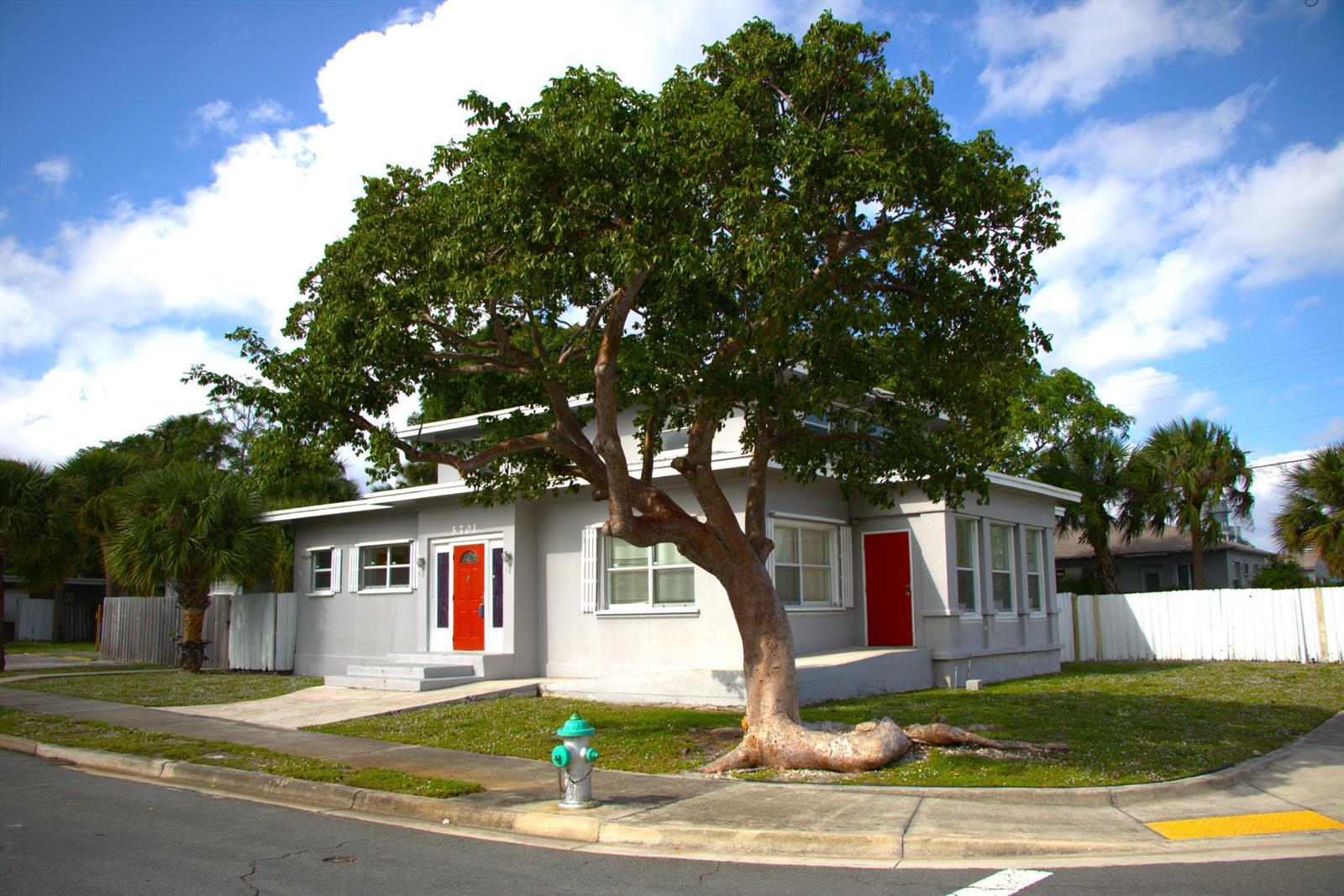 A two-story gray house with a large tree in the front yard and red doors — 5701 N Flagler Drive, West Palm Beach FL 33407, WEST PALM BEACH, FL