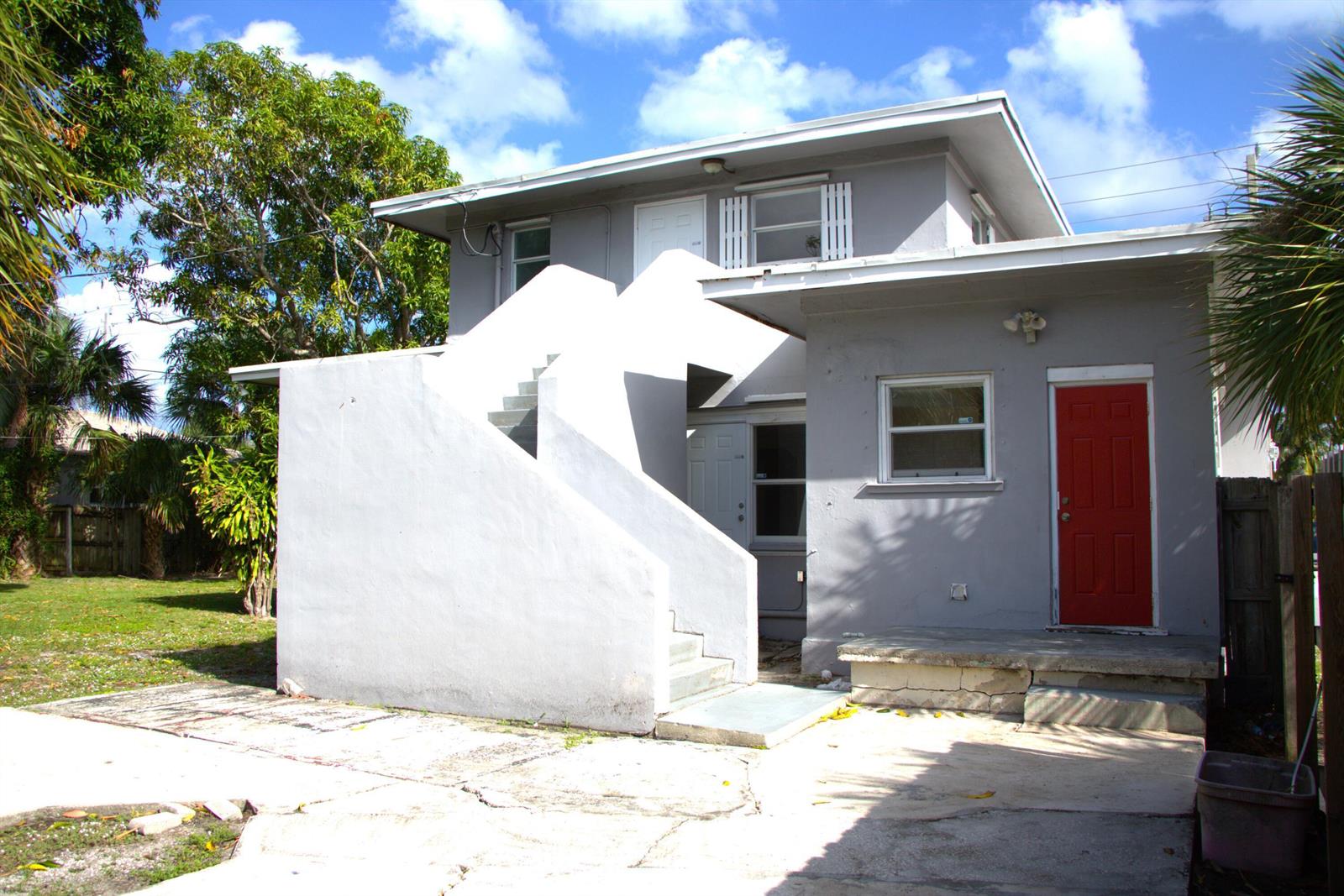 A two-story gray house features an exterior concrete staircase and a bright red front door — 5701 N Flagler Drive, West Palm Beach FL 33407, WEST PALM BEACH, FL