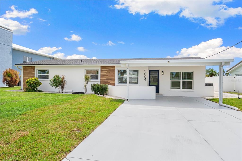 A single-story house with white stucco walls, wood-look siding accents, and a concrete driveway — 5004 ARLINGTON ROAD, PALMETTO, FL