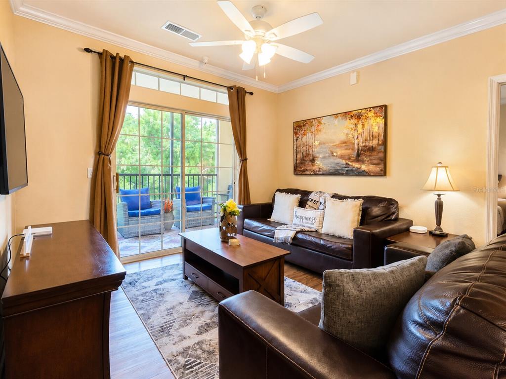 A living room features brown leather sofas, a wooden coffee table, and a sliding glass door — 8000 TUSCANY WAY UNIT 4207, DAVENPORT, FL