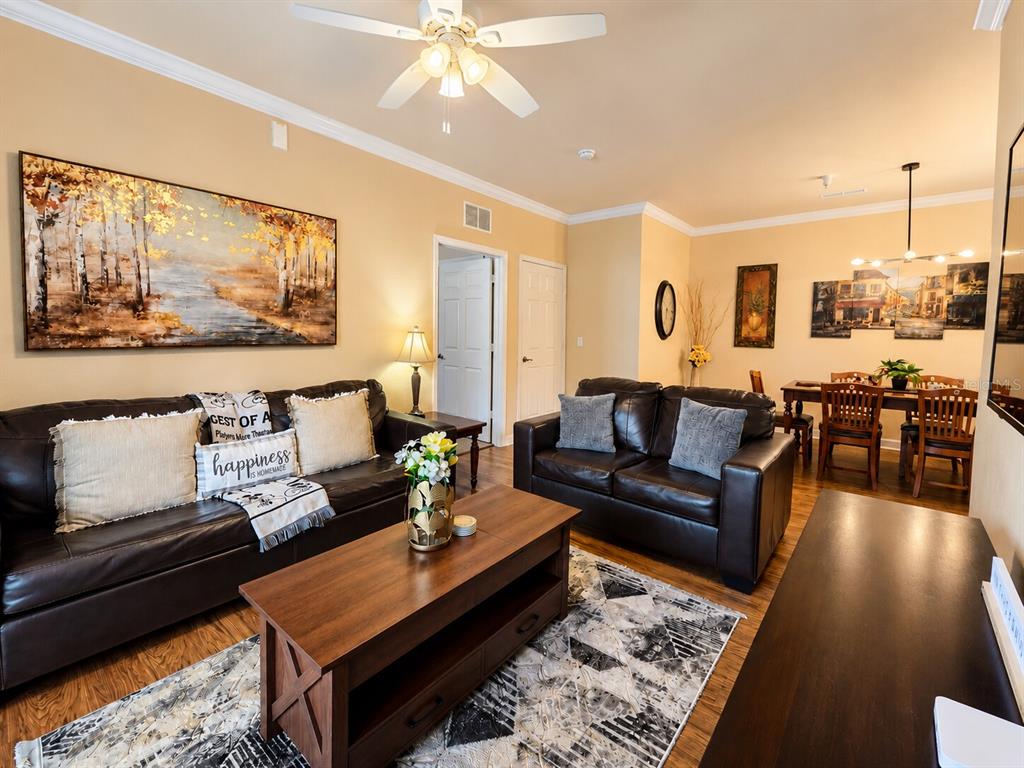 A living room features dark leather sofas, a wooden coffee table, and an adjacent dining area — 8000 TUSCANY WAY UNIT 4207, DAVENPORT, FL