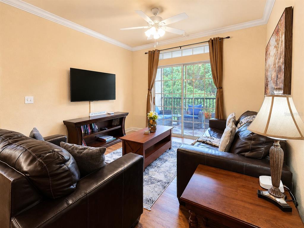 A living room features brown leather sofas, a television, a coffee table, and a balcony — 8000 TUSCANY WAY UNIT 4207, DAVENPORT, FL