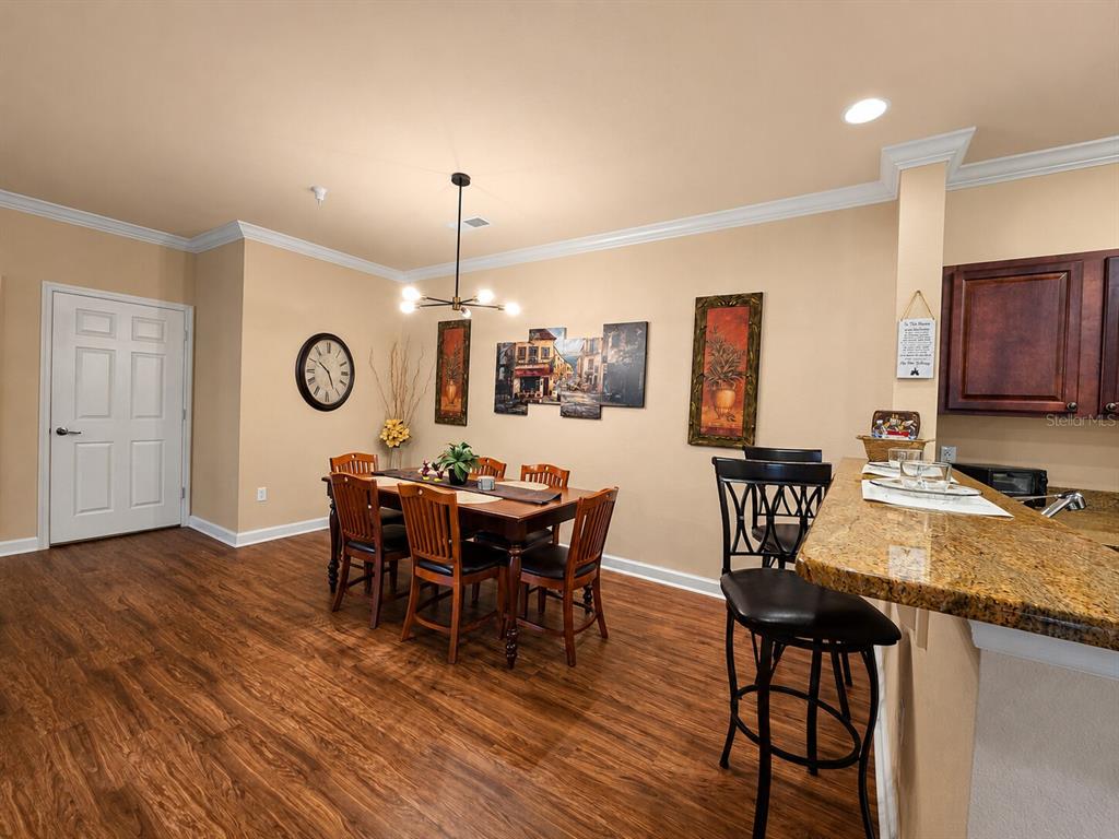 A dining area with a wooden table, chairs, and a breakfast bar with granite countertops — 8000 TUSCANY WAY UNIT 4207, DAVENPORT, FL