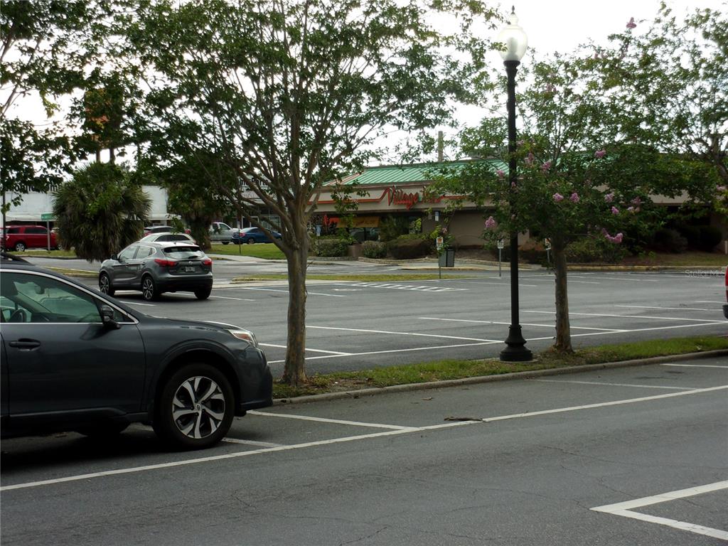 A parking lot with several parked cars and trees in front of a commercial building — 5208 7TH STREET, ZEPHYRHILLS, FL