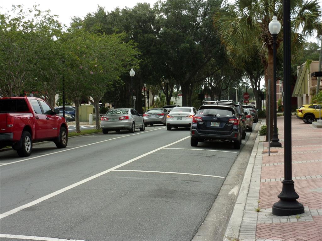 A street view shows parked cars along a road lined with trees and sidewalks — 5208 7TH STREET, ZEPHYRHILLS, FL