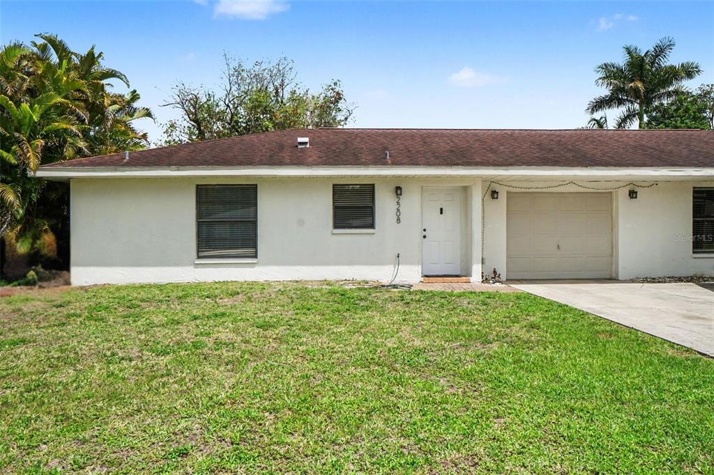 A single-story house with a white stucco exterior, a brown roof, and an attached garage — 2208/2210 IRIS WAY, FORT MYERS, FL
