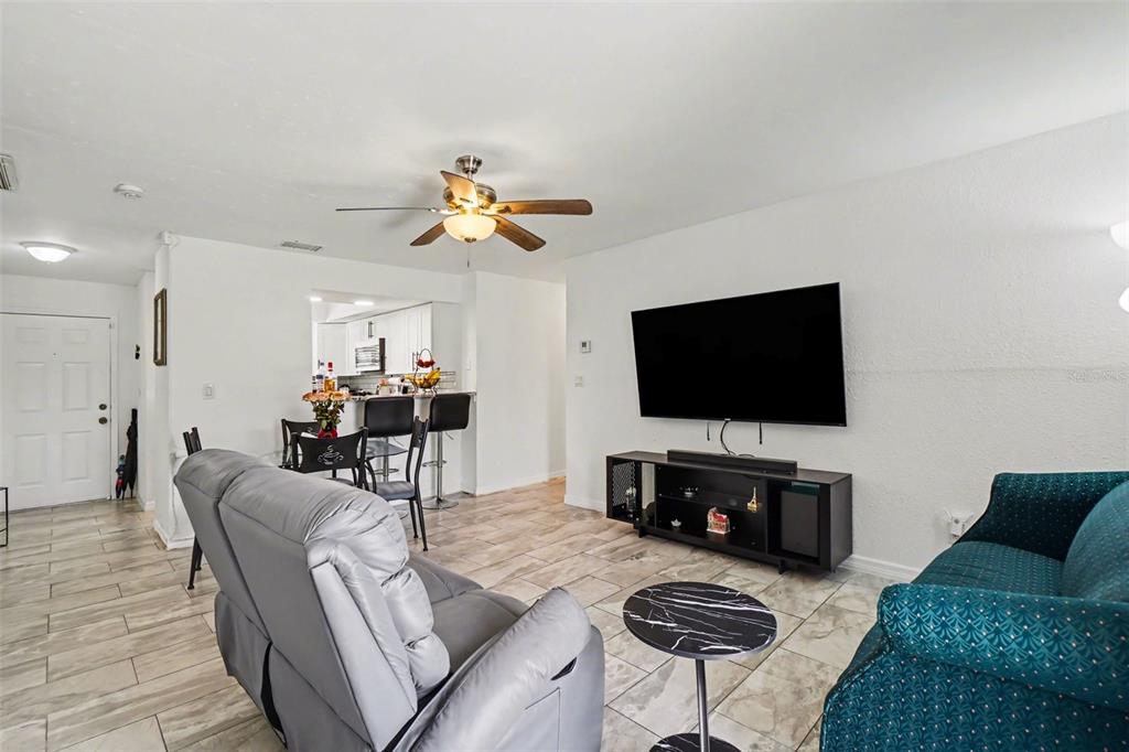 A living room with tile floors, a ceiling fan, a television, and a dining area — 2208/2210 IRIS WAY, FORT MYERS, FL