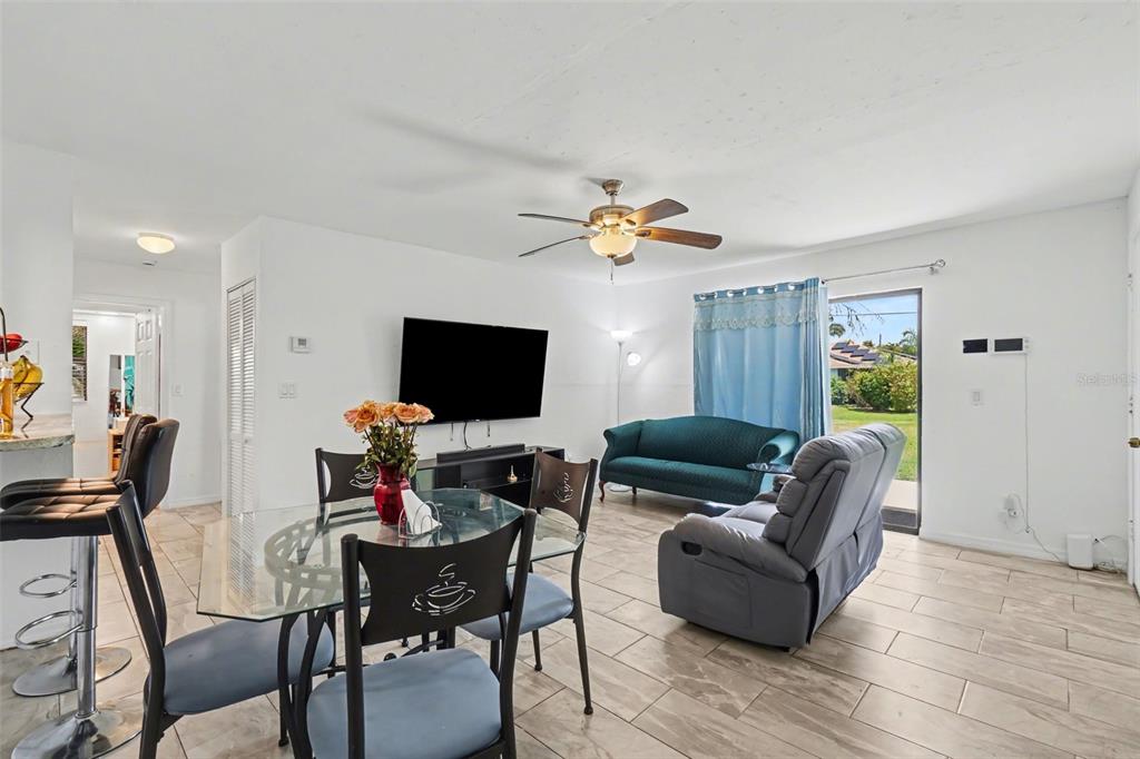 A living and dining area with tile floors, a ceiling fan, and a sliding glass door — 2208/2210 IRIS WAY, FORT MYERS, FL
