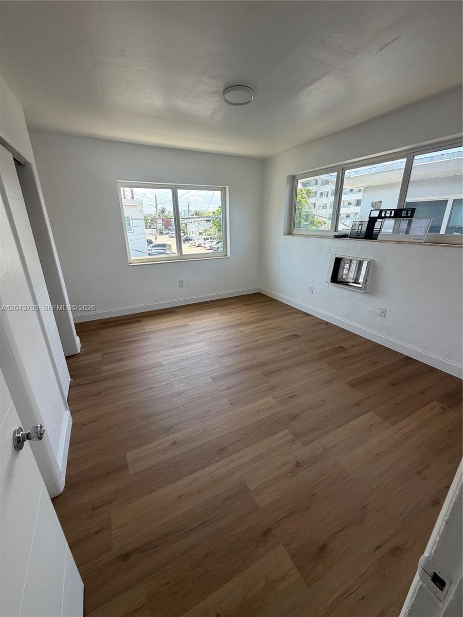 This bedroom features light wood-look flooring, white walls, and a window-mounted air conditioning unit — 780 73rd st # 74, Miami Beach FL 33141, MIAMI BEACH, FL