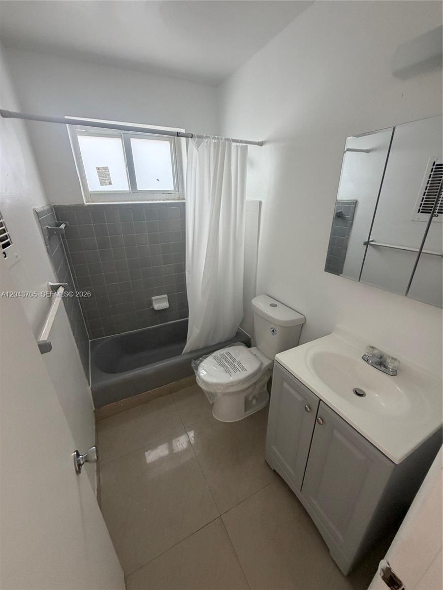 This bathroom features a gray vanity, a toilet, and a bathtub with gray tile walls — 780 73rd st # 74, Miami Beach FL 33141, MIAMI BEACH, FL