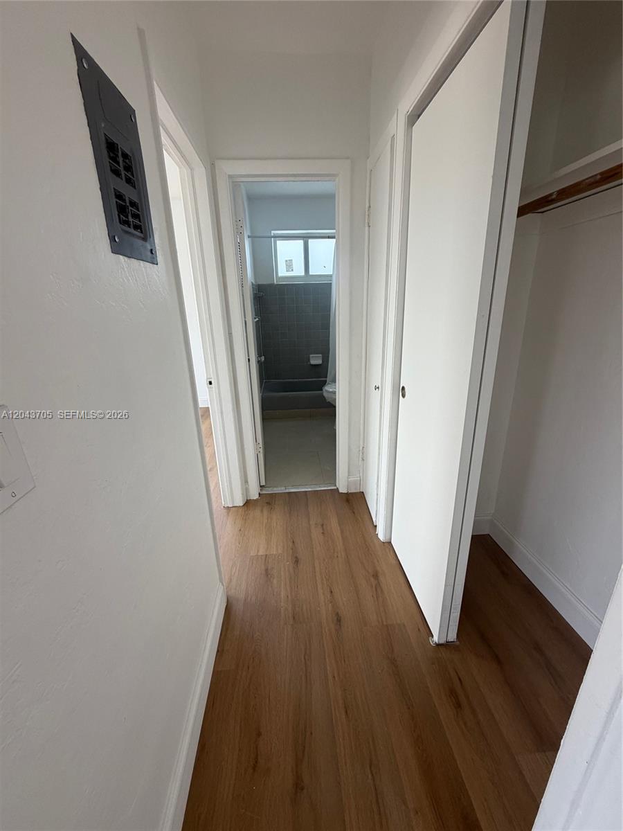 A hallway with wood-look flooring leads to a bathroom with a tiled shower — 780 73rd st # 74, Miami Beach FL 33141, MIAMI BEACH, FL