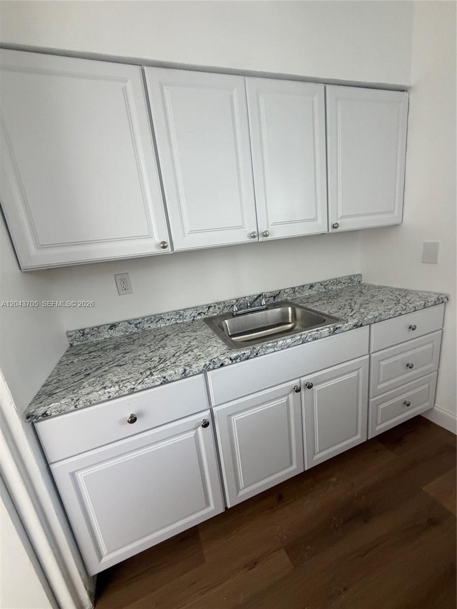 A kitchen features white cabinets, a granite countertop, and a stainless steel sink — 780 73rd st # 74, Miami Beach FL 33141, MIAMI BEACH, FL