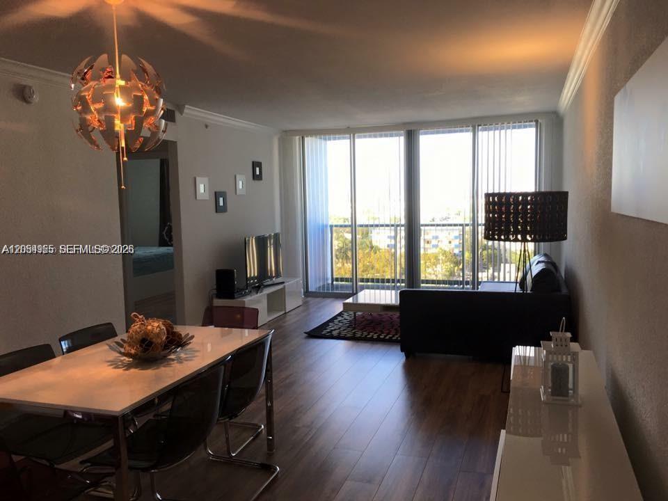 A living and dining area with wood floors, a modern chandelier, and floor-to-ceiling windows — 401 69th St # 905, Miami Beach FL 33141, MIAMI BEACH, FL