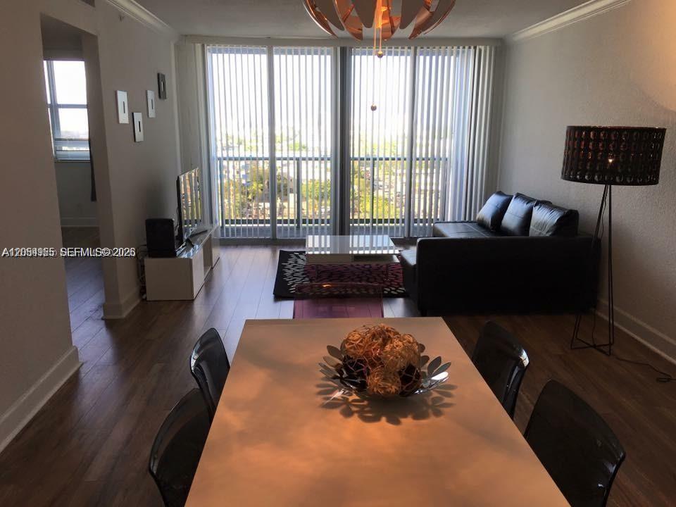 A dining area in the foreground leads to a living room with a balcony view — 401 69th St # 905, Miami Beach FL 33141, MIAMI BEACH, FL