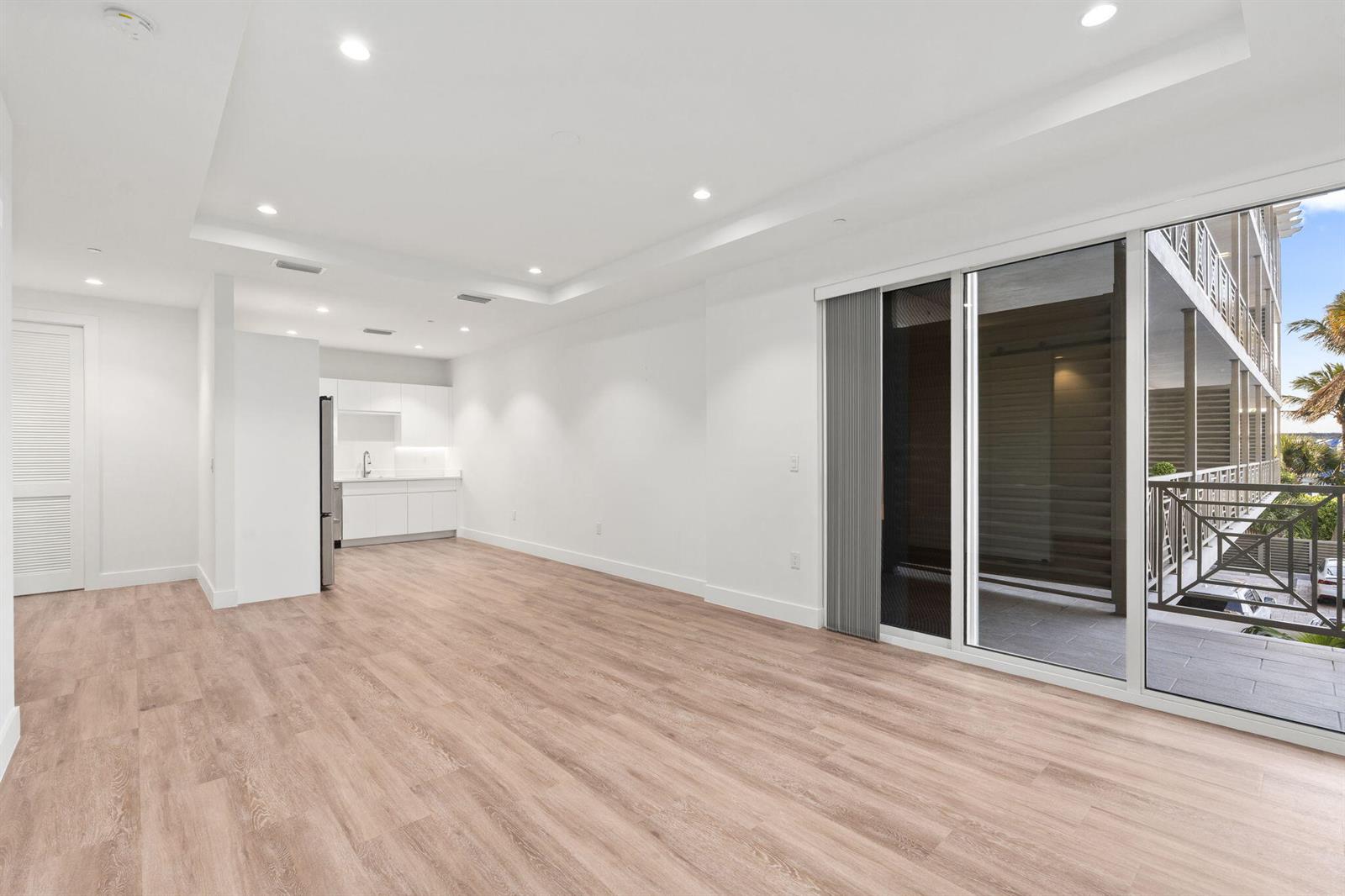 An empty room with light wood floors, recessed lighting, a small kitchen, and a balcony — 41 SW Seminole Street # 204, Stuart FL 34994, STUART, FL