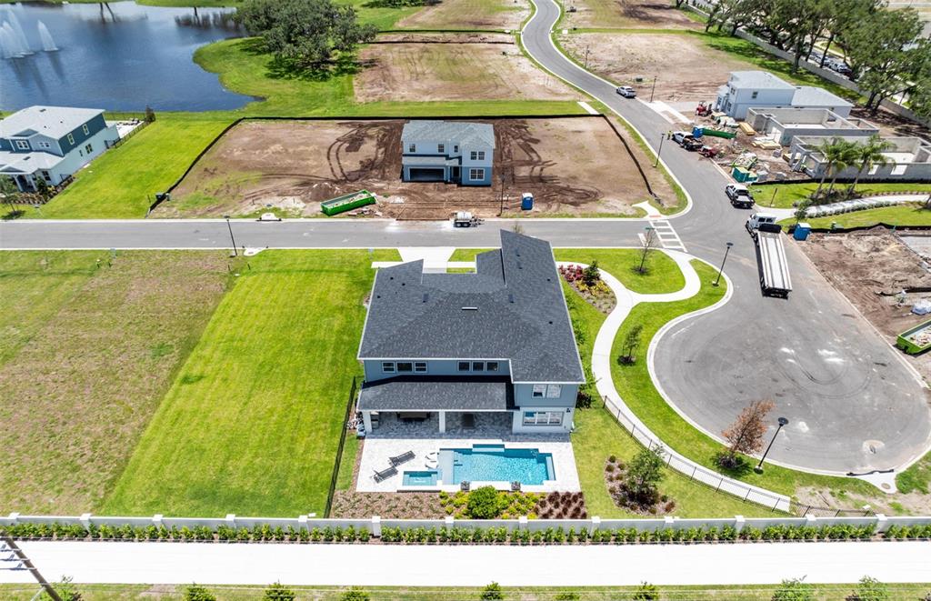 An aerial view shows a two-story house with a backyard pool and surrounding construction sites — 11205 CHANNELSIDE LANE, ORLANDO, FL