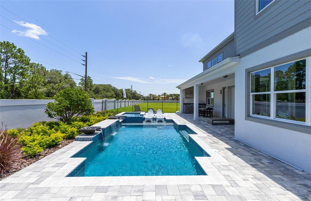 A backyard features a rectangular swimming pool with a spillover spa and a covered patio — 11205 CHANNELSIDE LANE, ORLANDO, FL