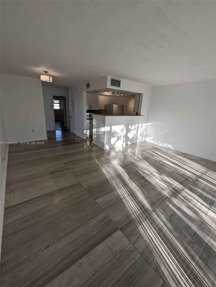 An open living area features large, wood-look tile flooring and a kitchen with a breakfast bar — 7360 SW 82nd St # E202, Miami FL 33143, MIAMI, FL