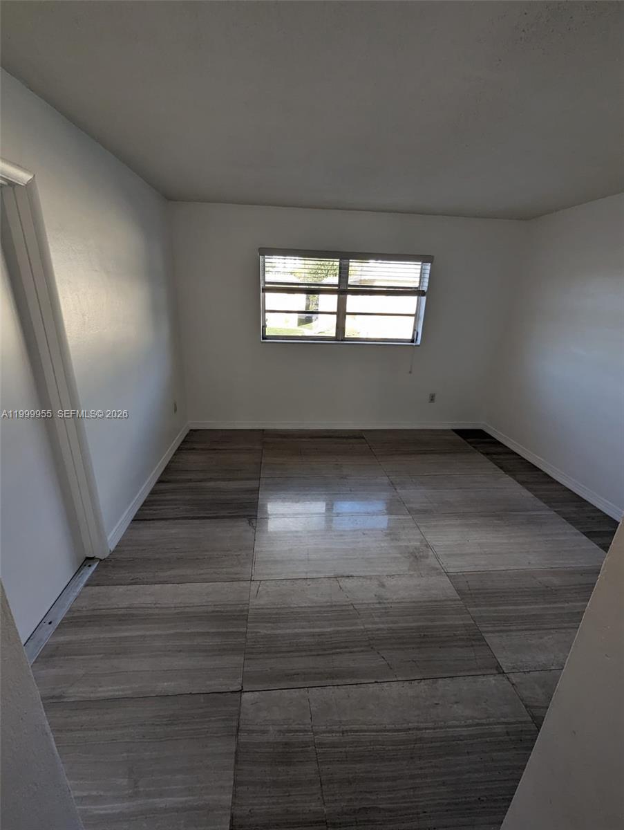 An empty room features white walls, a single window, and large, wood-look tile flooring — 7360 SW 82nd St # E202, Miami FL 33143, MIAMI, FL