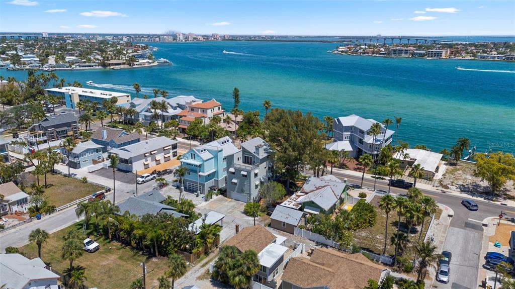 An aerial view shows coastal homes near a blue bay with a bridge in the distance — 1304 PASS A GRILLE WAY, ST PETE BEACH, FL