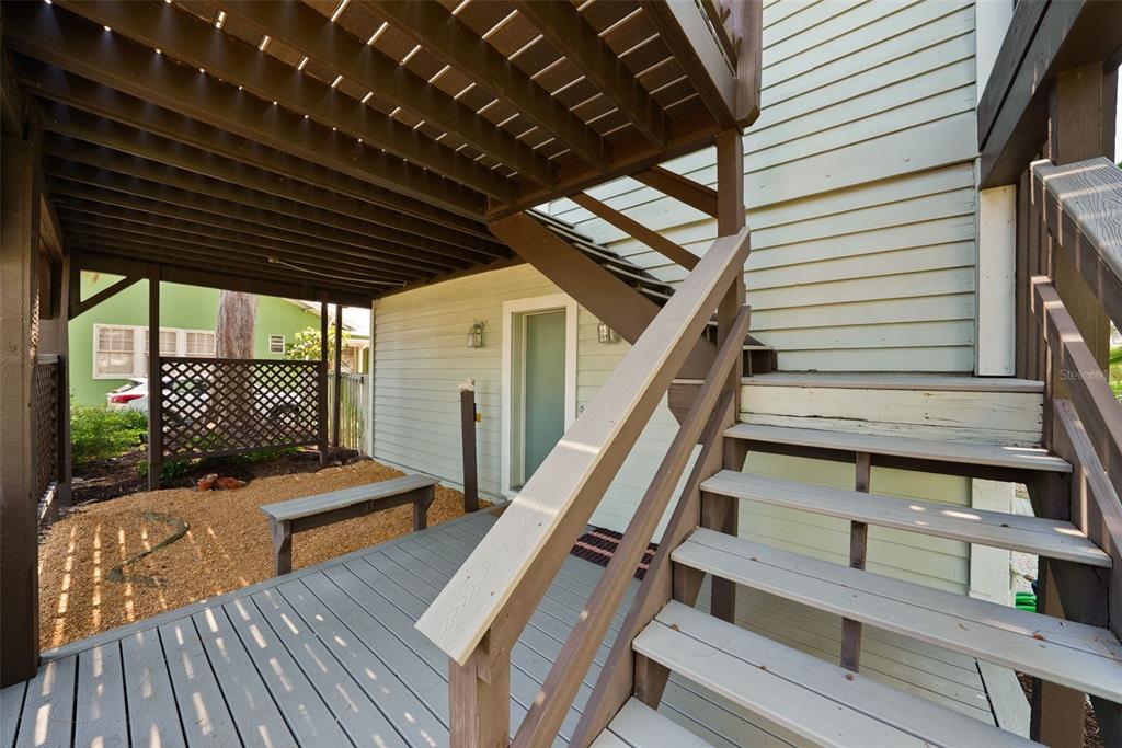 A covered patio features a gravel floor, wooden lattice privacy screens, and a light fixture — 1304 PASS A GRILLE WAY, ST PETE BEACH, FL