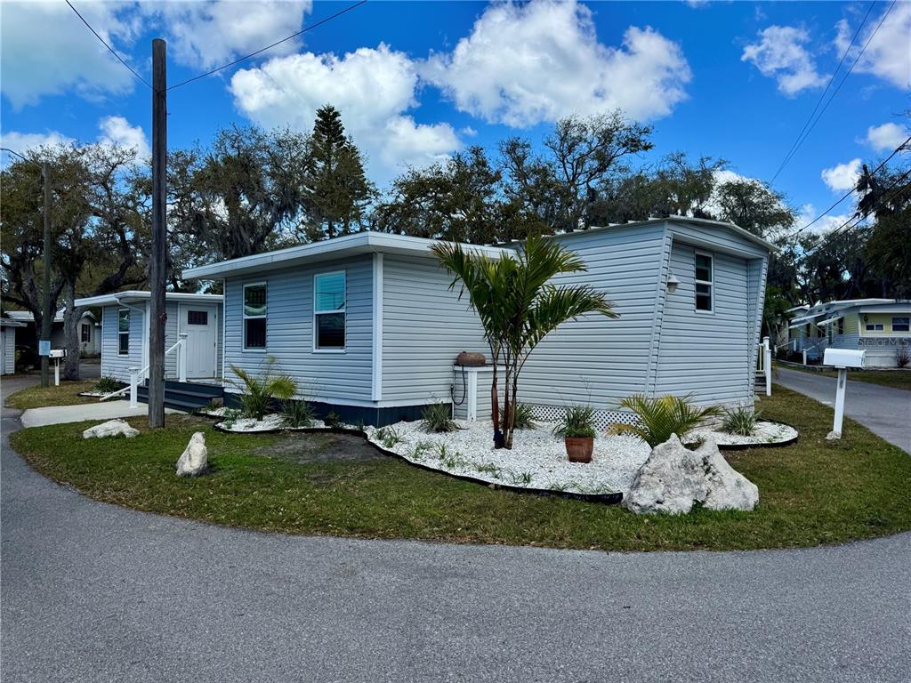 A light blue mobile home features white trim, a palm tree, and white rock landscaping — 15010 113TH AVENUE N UNIT 47, LARGO, FL